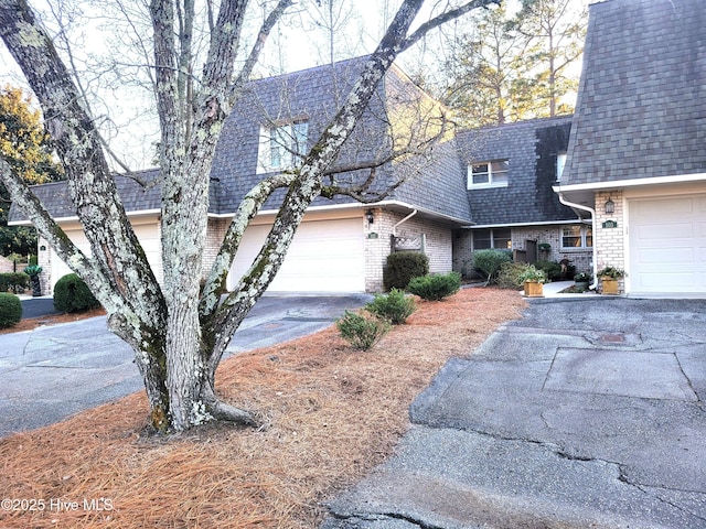 view of front of property with brick siding, driveway, and roof with shingles