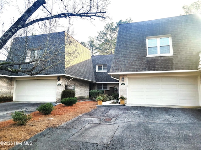 view of front of property with brick siding, driveway, and roof with shingles