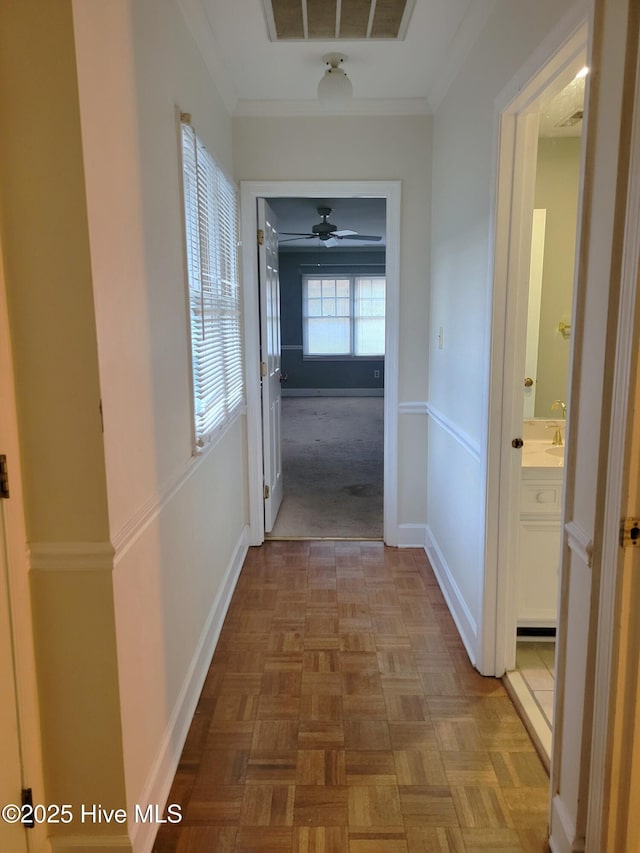 hall featuring visible vents, baseboards, and ornamental molding