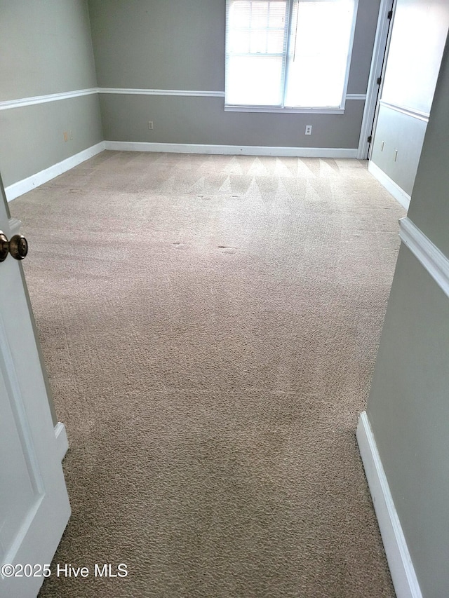 carpeted spare room featuring baseboards