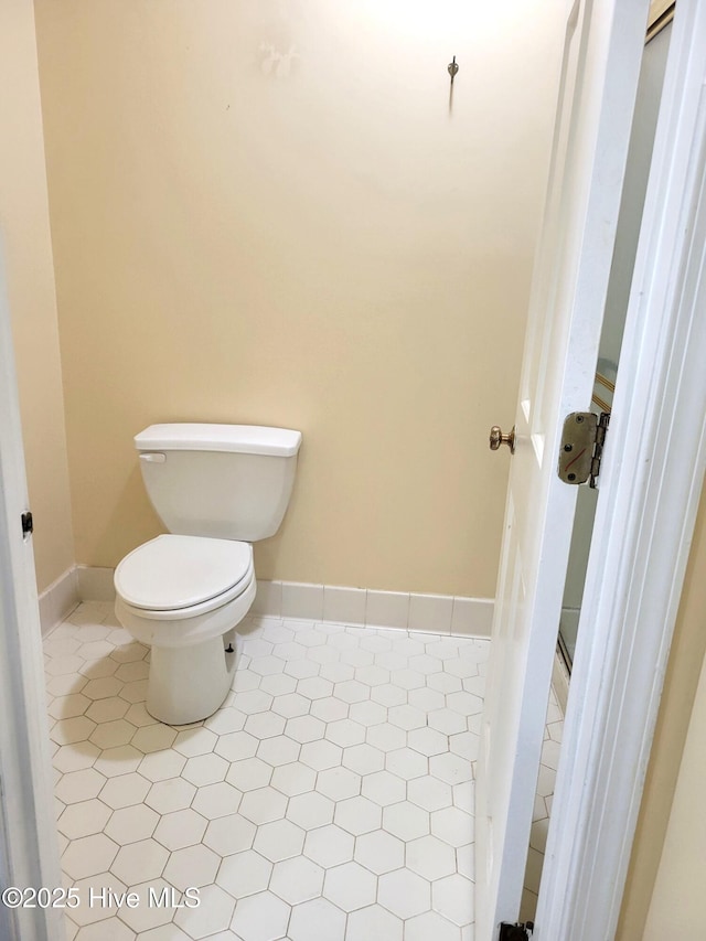 bathroom with tile patterned flooring, toilet, and baseboards