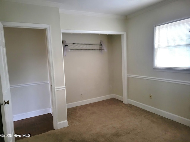 unfurnished bedroom featuring crown molding, baseboards, a closet, and carpet floors