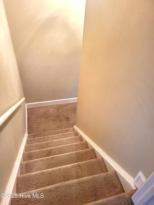 staircase featuring carpet flooring and baseboards