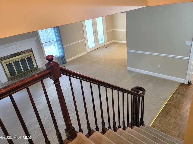 staircase with a glass covered fireplace, french doors, and baseboards