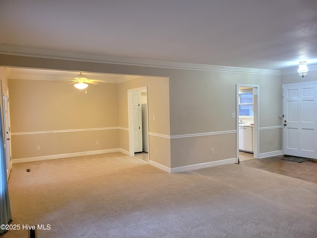 empty room with baseboards, light carpet, ceiling fan, and crown molding