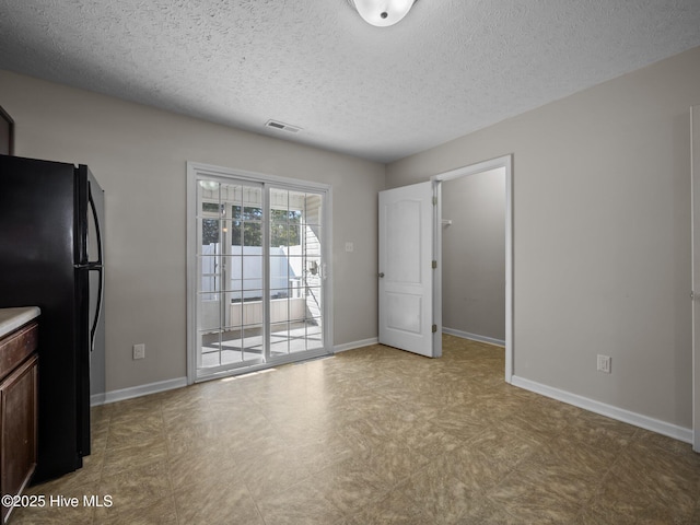 interior space with black fridge, a textured ceiling, and dark brown cabinets