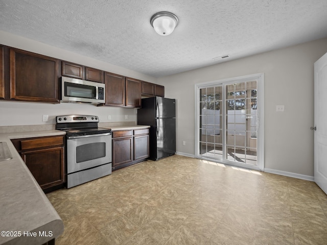 kitchen with a textured ceiling, stainless steel appliances, and dark brown cabinetry