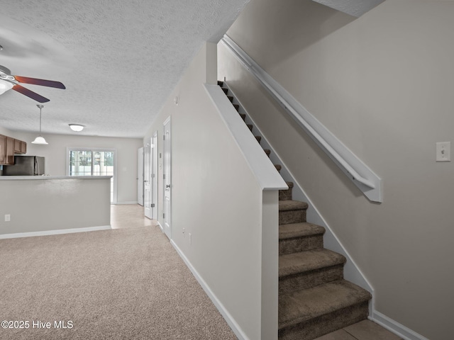 stairs featuring carpet floors, ceiling fan, and a textured ceiling