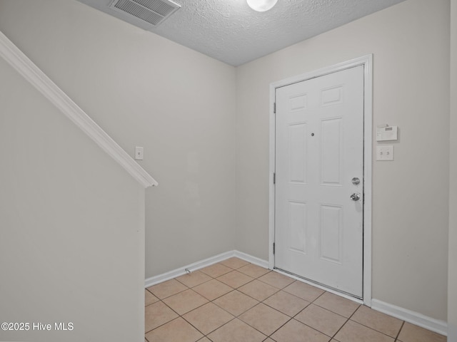 tiled entryway featuring a textured ceiling