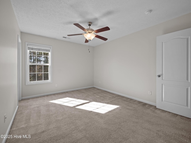 empty room with ceiling fan, light colored carpet, and a textured ceiling