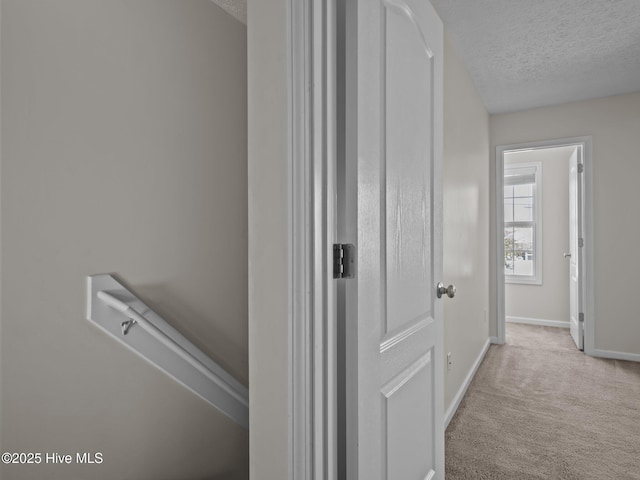 hallway featuring a textured ceiling and light colored carpet