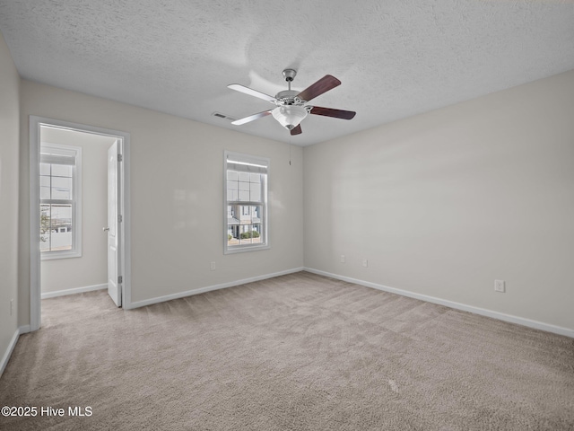 carpeted spare room featuring a textured ceiling, ceiling fan, and a wealth of natural light