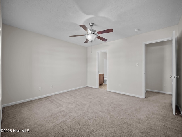 unfurnished bedroom featuring ceiling fan, ensuite bathroom, light carpet, and a textured ceiling