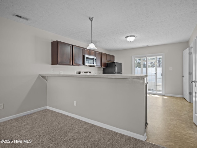 kitchen featuring decorative light fixtures, black fridge, kitchen peninsula, dark brown cabinets, and light colored carpet