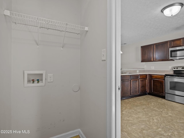 laundry area with a textured ceiling, hookup for a washing machine, and sink