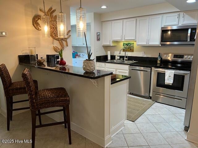 kitchen with stainless steel appliances, kitchen peninsula, sink, and white cabinets