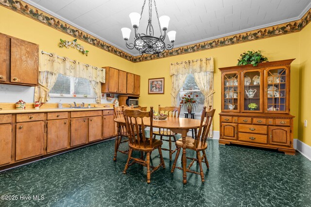 dining space with a chandelier, crown molding, and sink