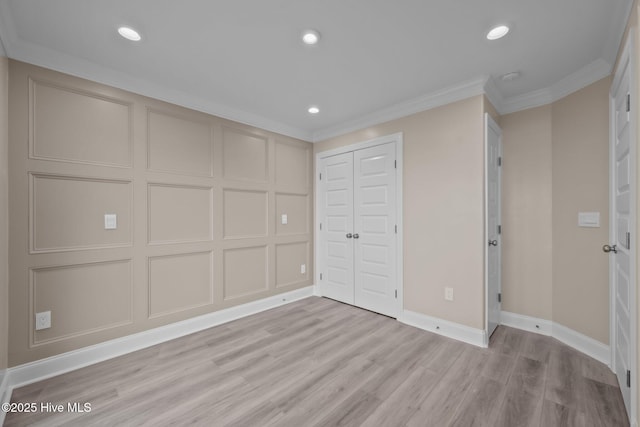 unfurnished bedroom with light wood-type flooring, ornamental molding, and a closet