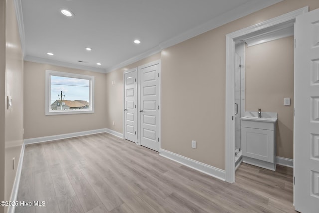 unfurnished bedroom featuring light hardwood / wood-style flooring, ensuite bath, crown molding, and sink