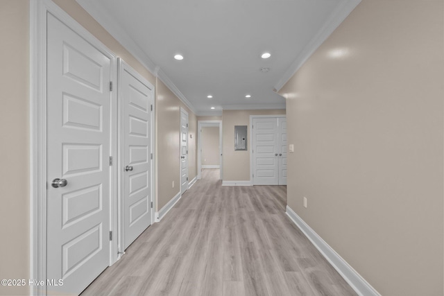 corridor featuring light wood-type flooring, ornamental molding, and electric panel