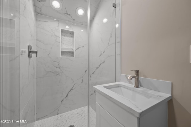 bathroom with a tile shower and vanity