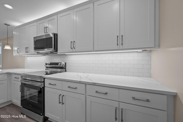 kitchen with decorative light fixtures, light stone countertops, stainless steel appliances, and dark wood-type flooring