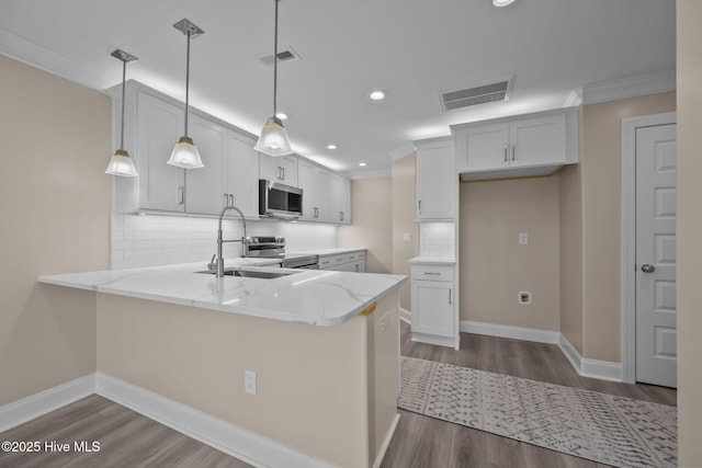 kitchen with kitchen peninsula, appliances with stainless steel finishes, white cabinets, and pendant lighting