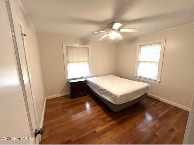 unfurnished bedroom featuring multiple windows, ceiling fan, and dark hardwood / wood-style flooring