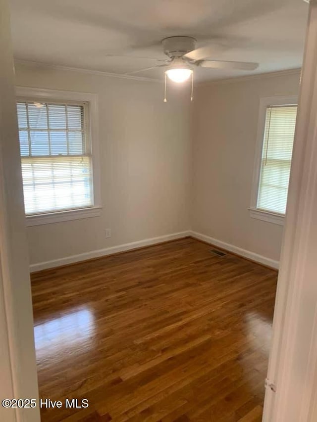 empty room featuring ceiling fan, crown molding, and dark wood-type flooring