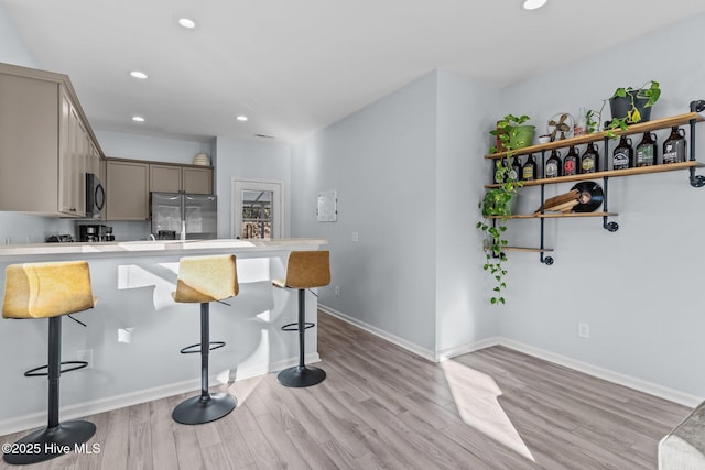 kitchen featuring a breakfast bar, stainless steel fridge with ice dispenser, and light hardwood / wood-style flooring