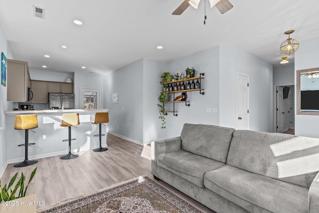 living room featuring light hardwood / wood-style flooring and ceiling fan with notable chandelier