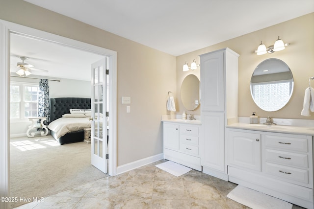 ensuite bathroom with a sink, two vanities, ensuite bath, and baseboards