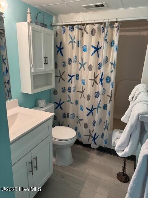 bathroom featuring toilet, shower / bathtub combination with curtain, vanity, and wood finished floors