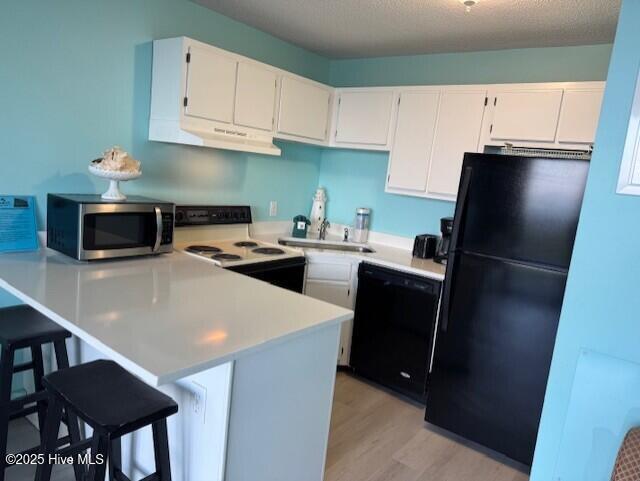 kitchen featuring visible vents, light countertops, white cabinets, a peninsula, and black appliances