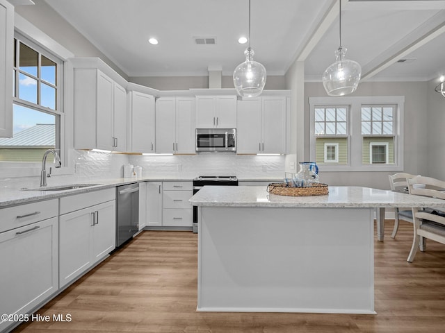 kitchen with decorative light fixtures, white cabinetry, sink, and appliances with stainless steel finishes