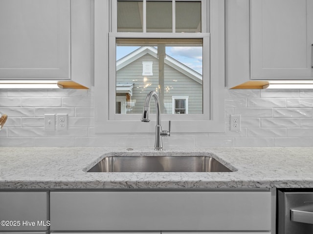 kitchen featuring decorative backsplash, light stone counters, white cabinetry, and sink