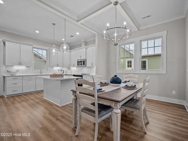 dining space with a wealth of natural light, light hardwood / wood-style flooring, and a chandelier