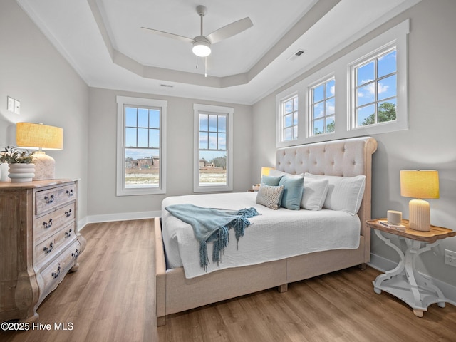 bedroom featuring ceiling fan, light hardwood / wood-style floors, and a raised ceiling