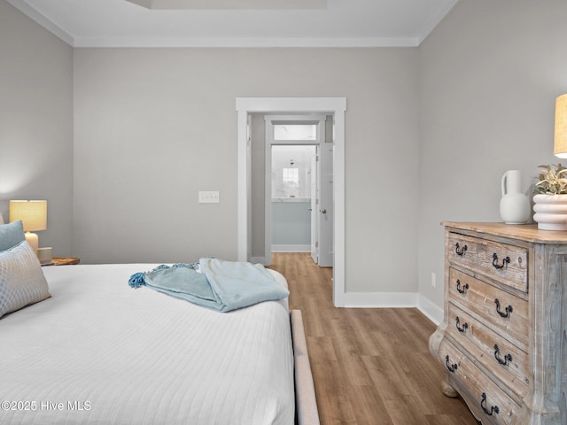 bedroom featuring ensuite bath, light hardwood / wood-style floors, and ornamental molding