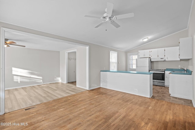 kitchen with stainless steel electric range oven, white cabinetry, open floor plan, and freestanding refrigerator