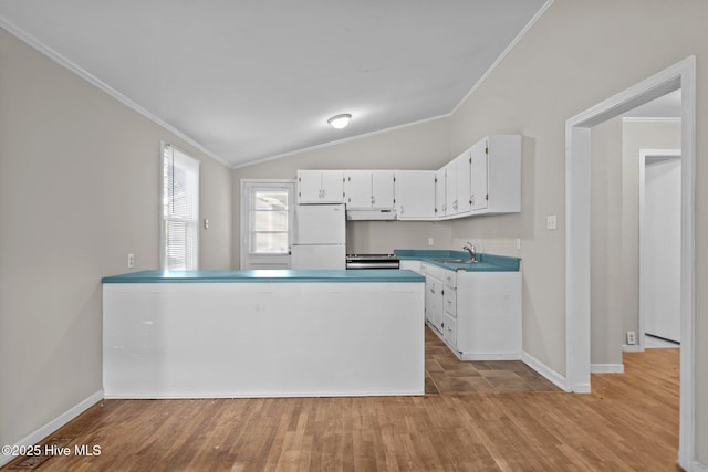 kitchen with light countertops, ornamental molding, freestanding refrigerator, white cabinetry, and a sink