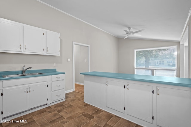 kitchen featuring a ceiling fan, lofted ceiling, light countertops, white cabinetry, and a sink