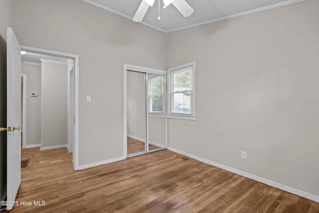 unfurnished bedroom with a closet, ornamental molding, a ceiling fan, wood finished floors, and baseboards