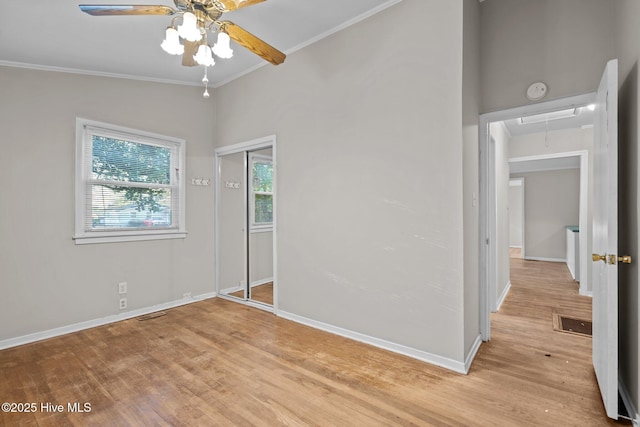 unfurnished bedroom with attic access, light wood-type flooring, crown molding, and baseboards