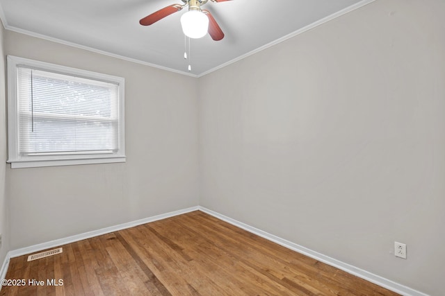 empty room with crown molding, visible vents, ceiling fan, wood finished floors, and baseboards