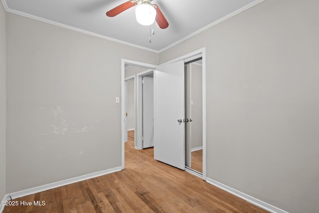 unfurnished bedroom with baseboards, ceiling fan, crown molding, light wood-style floors, and a closet