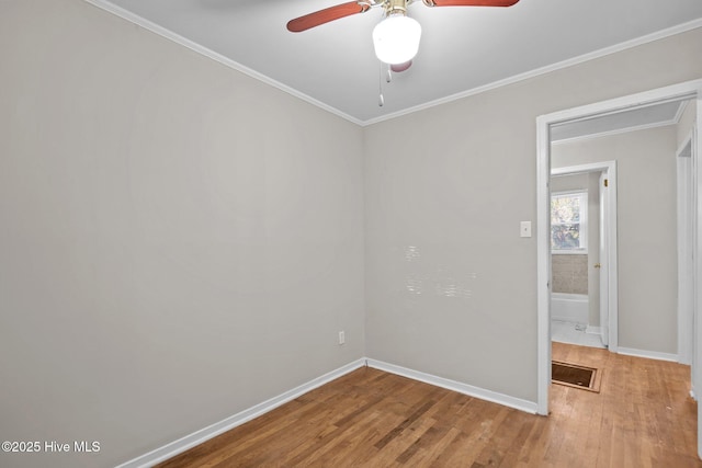 empty room featuring baseboards, visible vents, a ceiling fan, ornamental molding, and wood finished floors