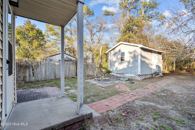 view of yard featuring a patio area, a fenced backyard, a fire pit, and an outdoor structure