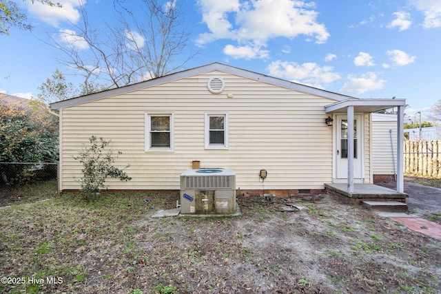 rear view of property featuring crawl space, cooling unit, and fence