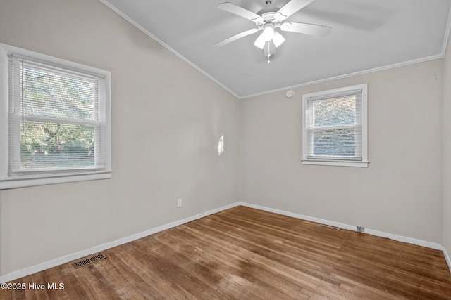 unfurnished room featuring a healthy amount of sunlight, visible vents, wood finished floors, and ornamental molding